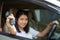 Asian car driver woman smiling showing new car key..Happy young girl owner taking car key from dealer in auto showÂ room.